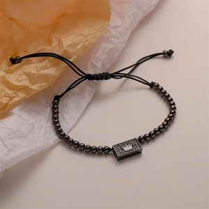 Detail of adjustable black woven bracelet with micro-pave crown charm and metallic beads