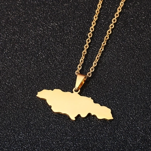 Detail shot of a golden Jamaica map pendant necklace on a textured black background