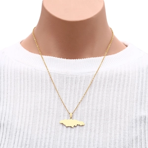 Close-up of a gold Jamaica map pendant necklace on a model wearing white knitwear