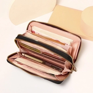 Black leather long wallet with double zippers and spacious card slots on beige background