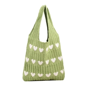 Close-up of green knitted tote bag with white heart pattern and soft wool texture