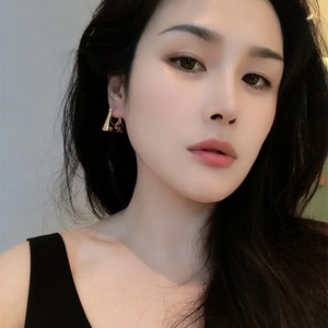 Vintage gold trapezoid earring featuring a dark brown floral pattern on a female model