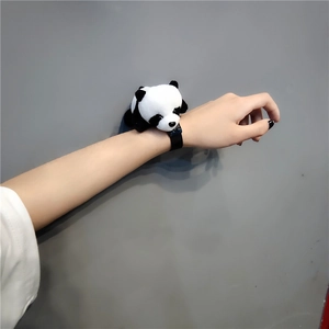 Close-up of a cute plush panda accessory worn on a wrist with an adjustable black strap