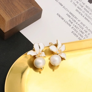 Macro detail of white flower earrings with pearls and zircons on a gold tray