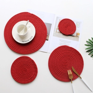 Detail of red woven cotton rope coasters and placemats on a clean white tabletop scene