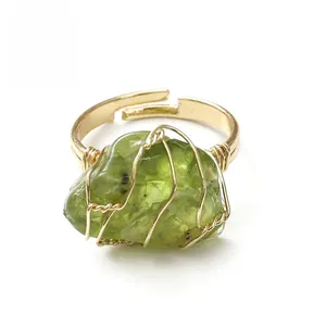 Macro detail of handmade gold wire-wrapped ring featuring raw green peridot stone