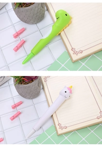 Detail of green bird and white unicorn squishy pens on a white grid desk setup