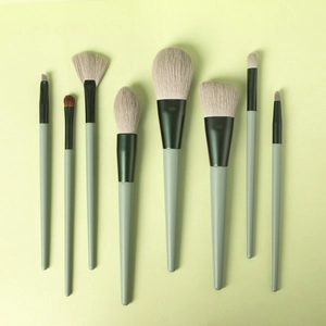 Detailed overhead shot of 8 professional green makeup brushes on matching background