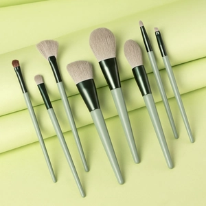 Detailed close-up of 8-piece makeup brush set with green handles on a matching paper backdrop
