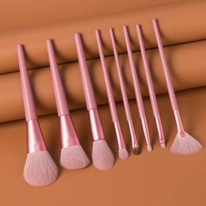 Close-up of 8-piece pink makeup brush set with metallic ferrules on a peach background