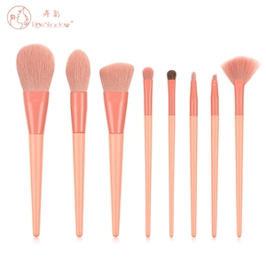 Flat lay of an 8-piece professional coral pink makeup brush set with matte handles