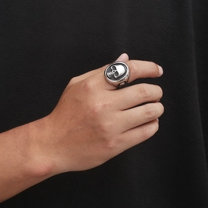 Close-up of a punk skull ring in silver stainless steel on a model hand with dark background