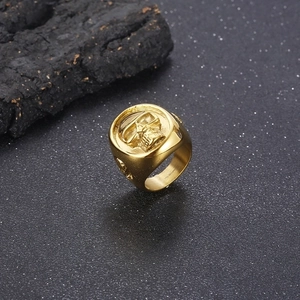 Detailed view of punk style gold plated stainless steel skull ring on a dark rock