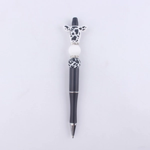 Detail of DIY beaded pen featuring a cute cow silicone topper and black and white beads