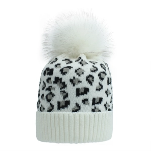 Detail of white knit beanie with black leopard print and fluffy faux fur pom-pom topper
