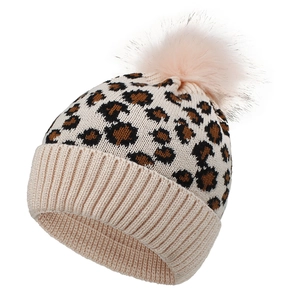 Detail of leopard print knit beanie featuring a fluffy faux fur pom-pom and ribbed cuff