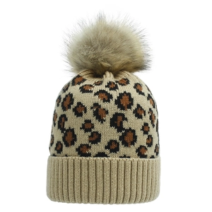 Close-up of leopard print knit beanie with large fluffy faux fur pompom and ribbed cuff
