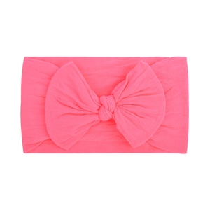 Detail of soft pink nylon headband with a large fabric bow for babies on white background