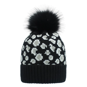 Close-up of leopard pattern knit beanie with large black faux fur pom pom and ribbed cuff