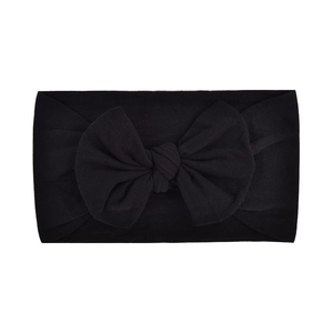 Detail of a soft black nylon baby headband with a large bow on a white background