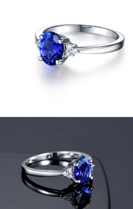 Detail view of oval royal blue sapphire ring with sparkling side stones in silver setting