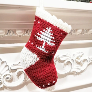 Detail of red and white knitted Christmas stocking with snowflake and tree patterns