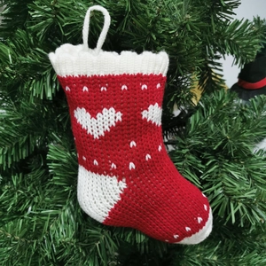 Detail of red and white knitted Christmas stocking with heart patterns on tree