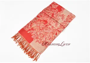 Detail of bohemian floral jacquard scarf featuring warm red tones and hand-tied tassels