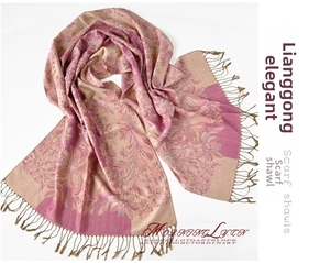 Close-up of bohemian scarf featuring pink and gold floral jacquard pattern and fringes