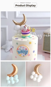 Macro detail of golden moon and white fuzzy ball clouds cake topper decoration