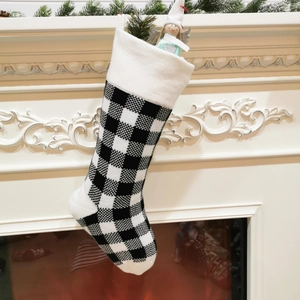 Classic 18-inch knitted black and white buffalo plaid Christmas stocking by the fireplace
