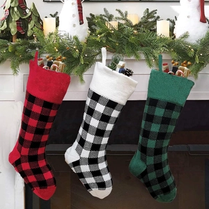 Three knit buffalo plaid Christmas stockings hanging on fireplace with festive decor