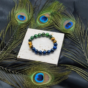 Tiger eye and malachite stone beaded bracelet on slate with peacock feathers