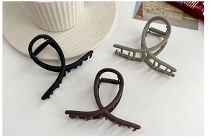 Close-up of three matte shark hair clips in black, brown and grey colors for hair styling