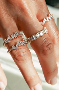 Macro shot of layered baguette-cut crystal rings with rose gold finish on a model's hand