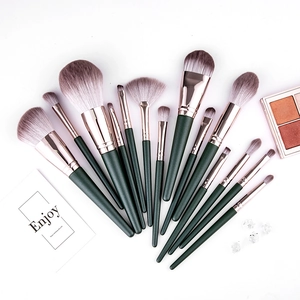 Macro view of 14-piece dark green makeup brush set with rose gold ferrules on white background