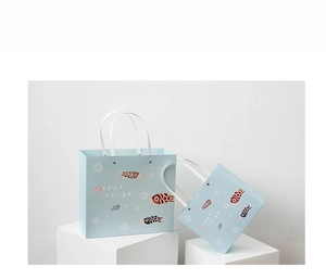 Detail view of light blue paper gift bags with koinobori illustration and white handles