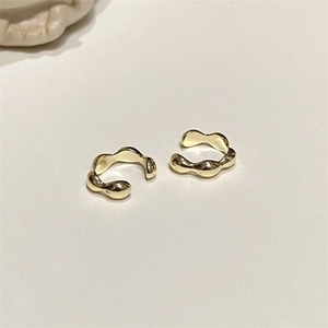 Close-up of minimalist wave-shaped gold ear cuffs with a modern irregular flowing curve