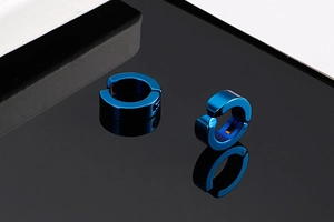 Vue détaillée de deux boucles d'oreilles clips bleu métallique sur fond noir poli