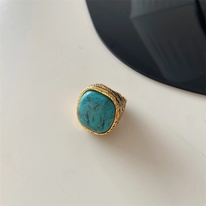 Top view of textured gold ring featuring a prominent turquoise stone on white background