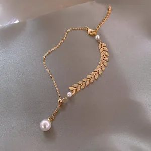 Detail shot of golden charm bracelet with pearl leaf elements on dark silk background