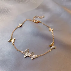 Detail of adjustable gold bracelet featuring polished and zircon butterfly charms on silk