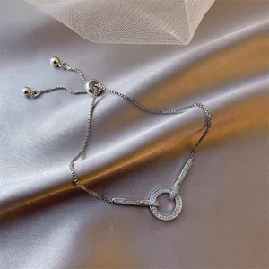 Detailed view of adjustable box chain bracelet with cubic zirconia ring on silk background
