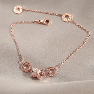 Detailed view of rose gold bracelet featuring micro-pave cylinder and engraved round charms