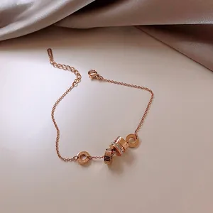 Detail of rose gold bracelet featuring Roman numeral rings and pavé white crystals