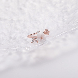 Detailed close-up of rose gold flower ring with shell petals and sparkling zircon accents