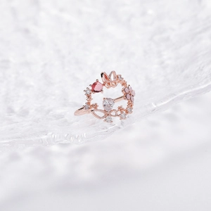 Close-up of rose gold ring with pink stones, zircons, and delicate butterfly and floral motifs