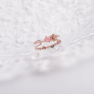 Detail of rose gold open ring with floral design and pink bead on crystal glass surface