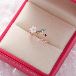 Detailed close-up of a rose gold flower ring with colorful crystals in a jewelry box