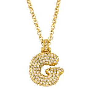 Close-up of golden letter G pendant necklace with white zircons on a rolo chain